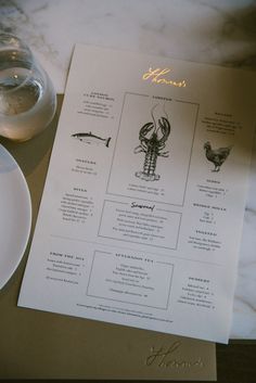 a menu with lobsters and other seafood on it next to a glass of water