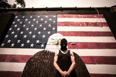 a man standing in front of an american flag painted on the side of a building