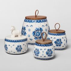 a set of four blue and white ceramic containers with wooden lids, one has a horse figurine on top