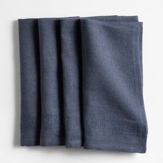 three folded napkins on top of each other, one in blue and the other in grey