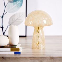 a mushroom lamp sitting on top of a wooden table next to books and other items