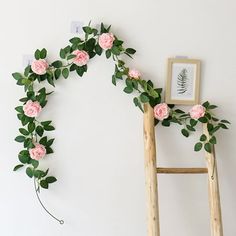 a ladder decorated with pink flowers and greenery next to a framed photograph on the wall