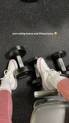 the feet of a person who is standing next to some dumbs on a treadmill