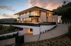 a modern house is lit up at night with lights on the windows and balconies