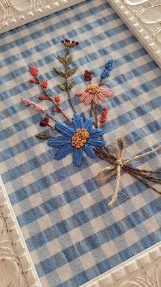 a blue and white checkered table cloth with flowers on it