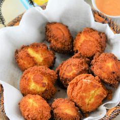 a basket filled with fried food next to a cup of sauce