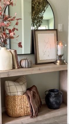 a wooden shelf topped with a mirror next to a vase filled with flowers and other items