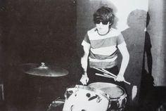 a man standing next to a drum set