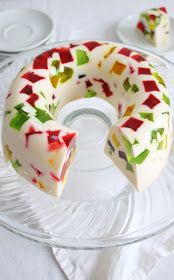 a cake with white frosting and multicolored toppings on a glass plate