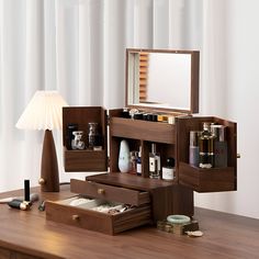 a wooden desk topped with drawers filled with cosmetics and personal care items next to a lamp