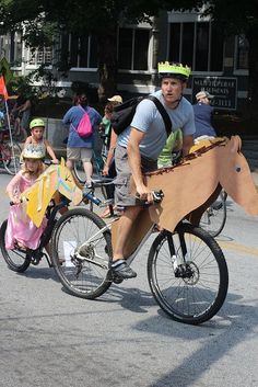 a man riding a bike with a cardboard box on it's back while carrying a child