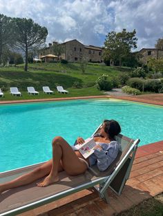 a woman is lounging by the pool reading a magazine