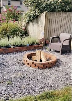 a fire pit in the middle of a graveled area next to a wooden fence