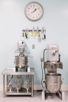 two mixers sitting next to each other in front of a wall with a clock