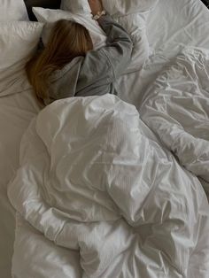 a woman laying in bed with her head on the pillow