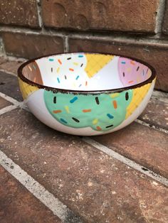 a bowl with sprinkles on it sitting on a tile floor next to a brick wall