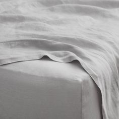 an unmade bed with white sheets and pillows