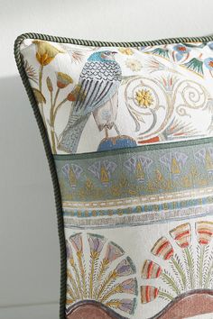 a decorative pillow with a bird sitting on it's back and colorful designs on the front