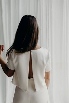 the back of a woman's white dress, with her hands on her hips