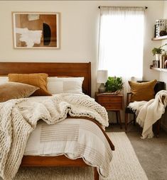 a bed room with a neatly made bed next to a window and a painting on the wall