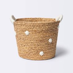 a large woven basket with white flowers on the handles and sides, sitting on a white surface