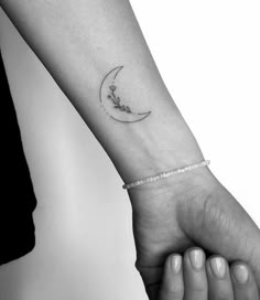 a woman's arm with a small crescent tattoo on the left side of her wrist