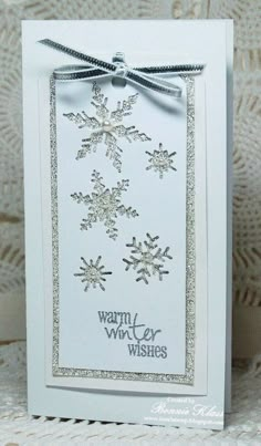 a white card with snowflakes on it and a ribbon around the edge that says warm wishes