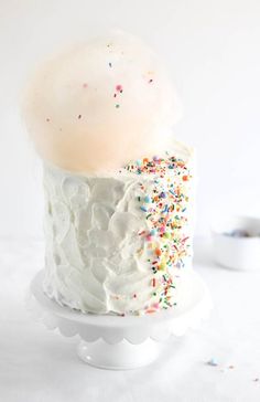 a cake with white frosting and sprinkles sitting on top of a plate