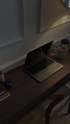 an open laptop computer sitting on top of a wooden desk next to a cup of coffee