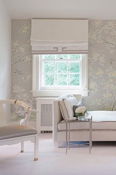 a living room filled with furniture next to a wallpaper covered in white and pink flowers