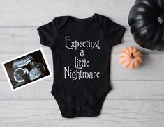 an infant's bodysuit with the words expecting a little nightmares next to it