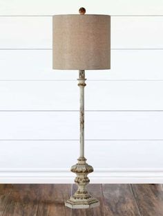 a lamp on a wooden floor in front of a white wall and wood flooring