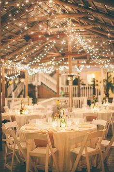 tables and chairs are set up for an event with string lights strung over the ceiling