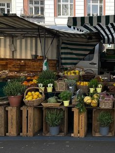 an open air market with fruits and vegetables on the tables, under awnings