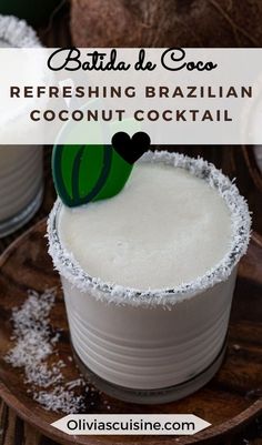 a close up of a drink in a glass on a plate with coconuts around it