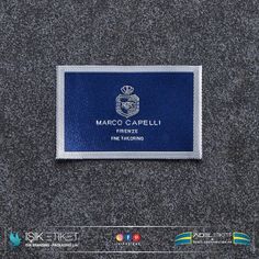 a blue and white business card sitting on top of a gray carpeted floor with the name marco capelli printed on it