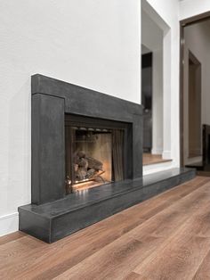 a fire place in the middle of a room with wood flooring and white walls