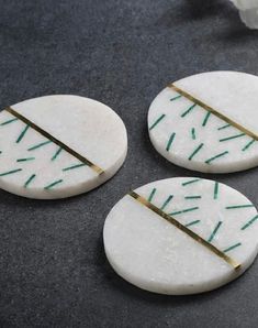 three pieces of white marble with green lines on them, sitting next to a flower