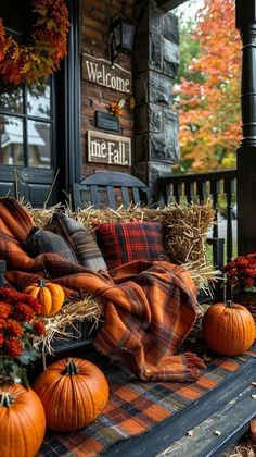 pumpkins and hay bales are arranged on the front porch for fall decorating