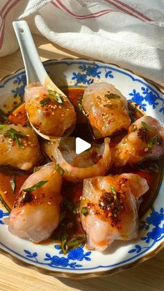 a blue and white plate topped with shrimp next to a wooden table covered in sauce