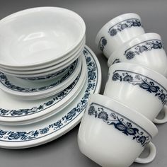 a stack of white and blue china cups and saucers on a gray tablecloth