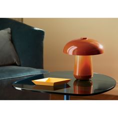 a mushroom lamp sitting on top of a glass table next to a blue couch in a living room