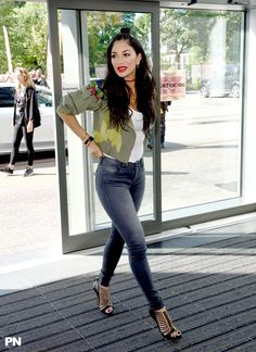 a woman standing in front of a glass door with her hands on her hips and wearing high heels