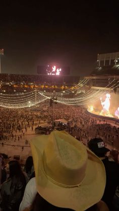 a large crowd at a concert in the middle of an arena with lights on it