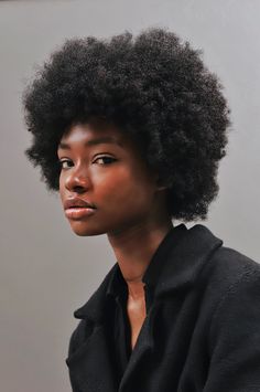 a woman with an afro looks at the camera