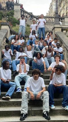 a group of young men sitting on top of steps in front of some buildings with their hands up