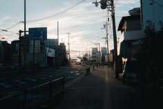 an empty city street with power lines above and buildings on both sides, in the distance