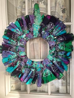 a purple and green wreath sitting on top of a window sill in front of a white door