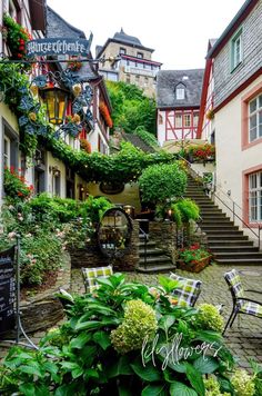 an outdoor area with tables, chairs and flowers on the steps in front of buildings