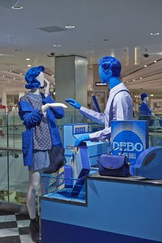 two mannequins dressed in blue and white are standing behind a display case